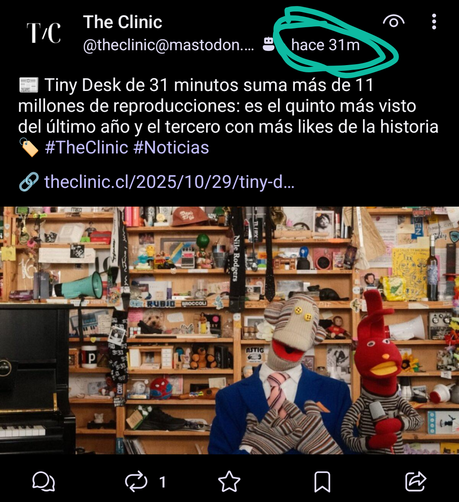 Una captura de pantalla de una publicación de redes sociales de "The Clinic". El texto principal indica: "Tiny Desk de 31 minutos suma más de 11 millones de reproducciones: es el quinto más visto del último año y el tercero con más likes de la historia", seguido de los hashtags #TheClinic #Noticias y un enlace.
Debajo del texto, hay una imagen que muestra un estudio o habitación muy desordenado y ecléctico, lleno de estantes de madera repletos de objetos variados como libros, instrumentos musi…
