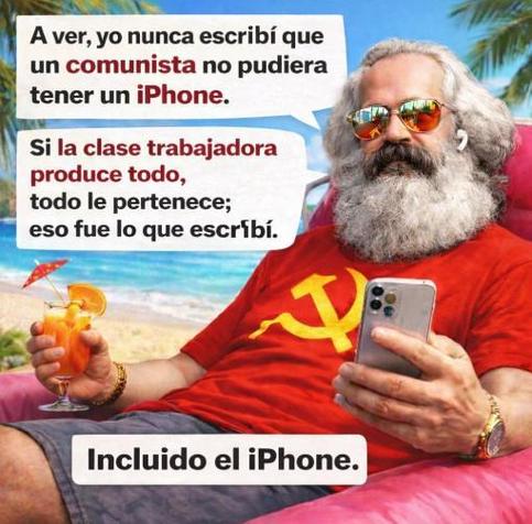 La imagen muestra a un hombre que se asemeja a Karl Marx, con cabello largo y barba blanca, gafas de sol y una camiseta roja con el símbolo de la hoz y el martillo. Está relajado en una silla de playa en un entorno tropical con el mar de fondo, sosteniendo un cóctel con sombrilla en una mano y un iPhone moderno en la otra. Dos bocadillos de diálogo y un texto al pie lo acompañan. El primer bocadillo dice: "A ver, yo nunca escribí que un comunista no pudiera tener un iPhone." El segundo añade: "…