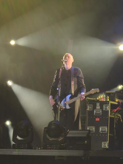 Billy Cortan cantando frente al micrófono mientras toca guitarra.