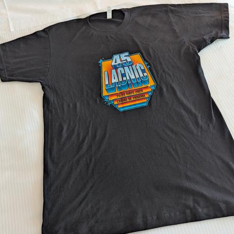 Una camiseta negra, vista desde arriba, con un logo colorido y estilizado en el pecho. El logo tiene un efecto 3D y un estilo retro, mostrando el número "45" sobre la palabra grande "LACNIC" en tonos naranja y azul. Debajo, en franjas azules, se leen las fechas "25-28 MAYO 2026" y el lugar "CIUDAD DE PANAMA". El diseño incluye pequeños destellos a su alrededor.